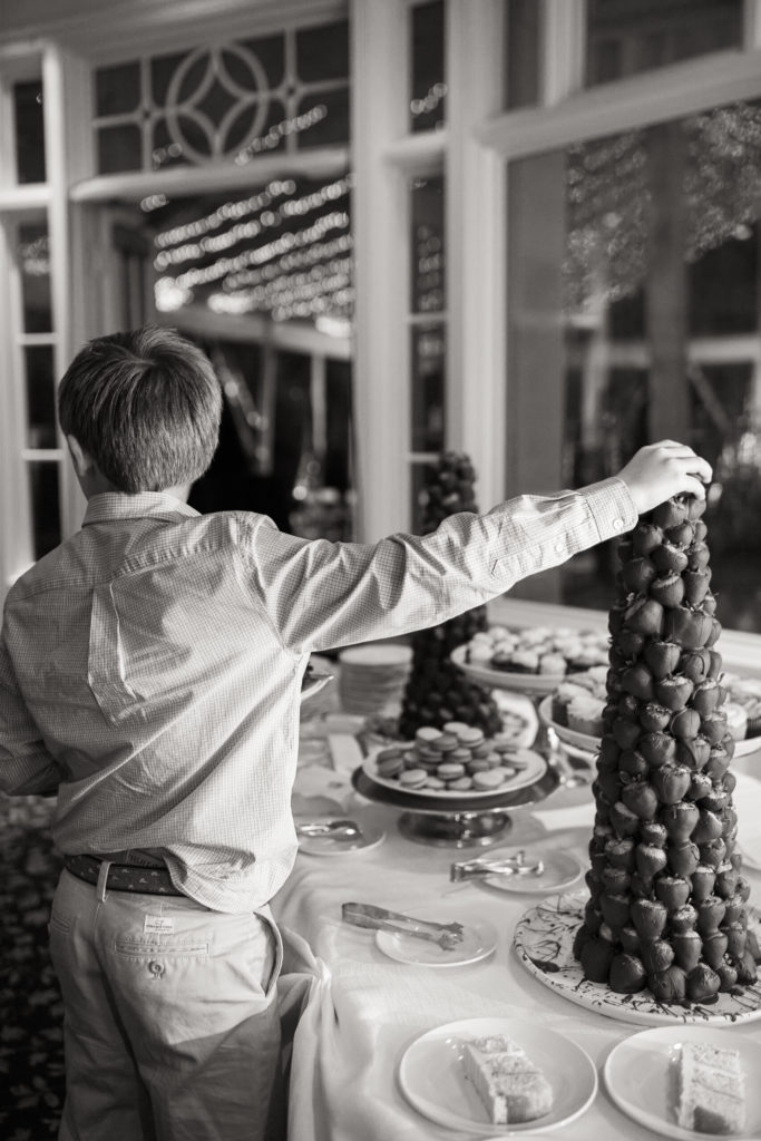 Young wedding guest helping self to a dessert